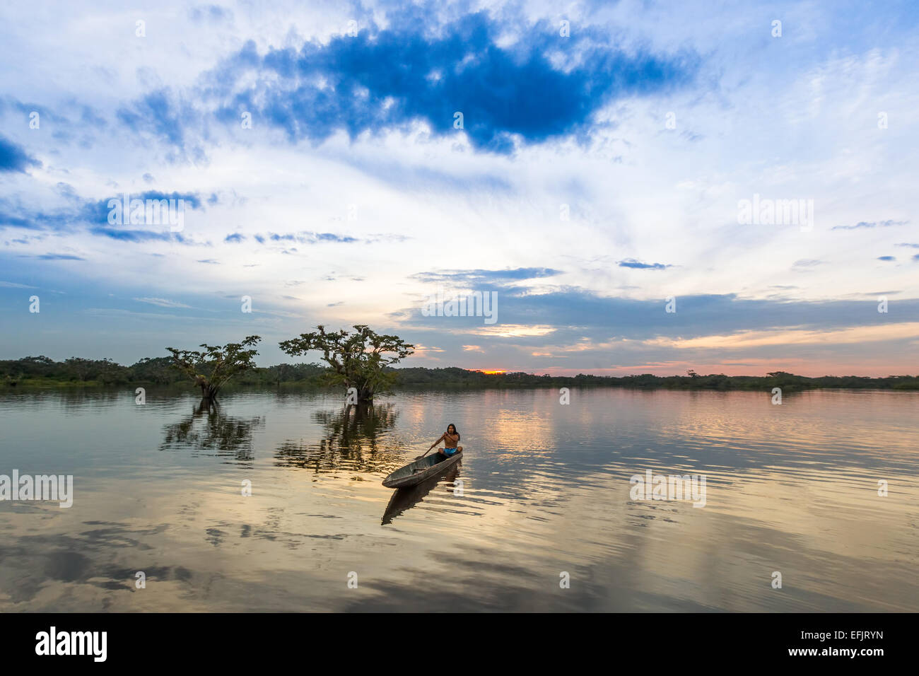 Cuyabeno National Park Sucumbios Ecuador Indigenous Adult Man With Wood Canoe Against Blue Sunset Sky Stock Photo