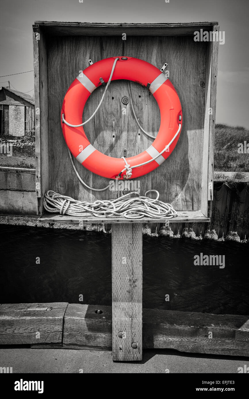 Orange life saver or buoy hanging in wooden box on dock. Prince Edward Island, Canada, selective coloring. Stock Photo