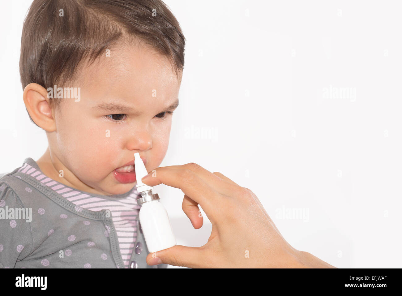 parent's hand of a sick little girl applies a nasal spray Stock Photo
