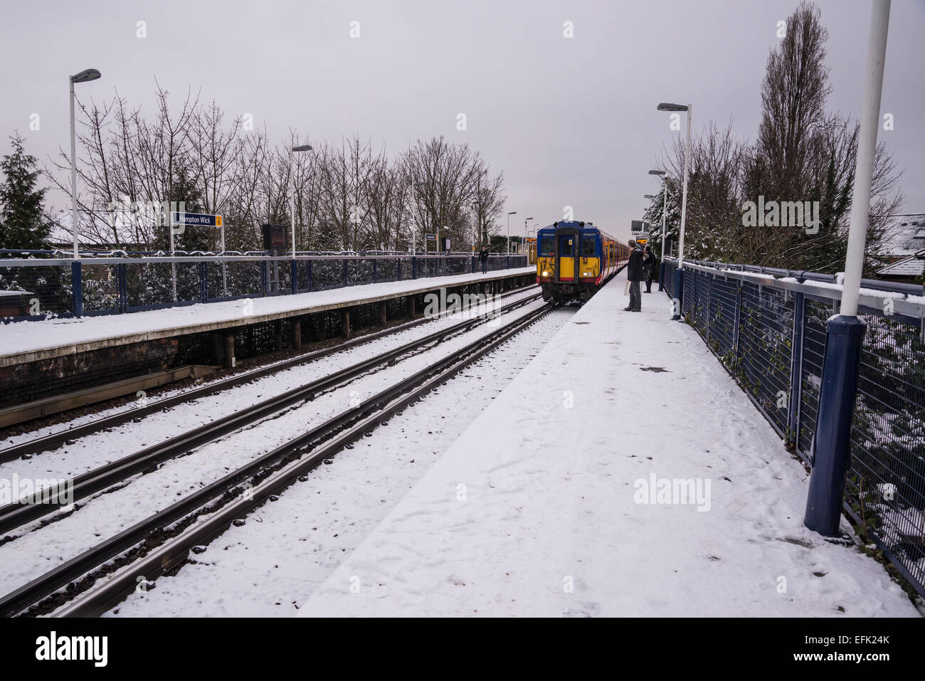 Train coming into suburban train station covered in light snow, Hampton Wick, Surrey, England, UK Stock Photo