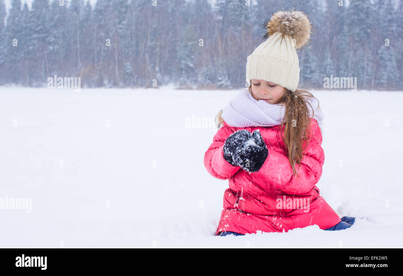 Happy adorable little girl playing snowballs in snowy winter day Stock ...