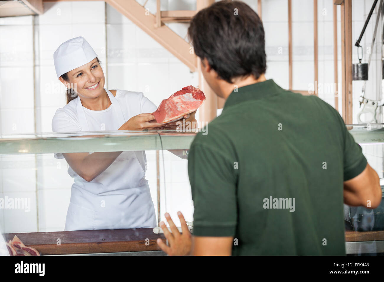 Female Butcher Selling Fresh Meat To Customer Stock Photo