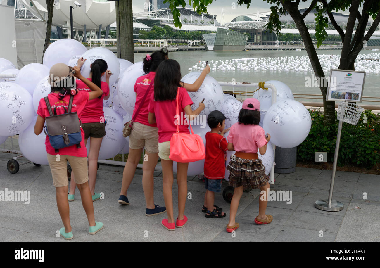 Singaporeans writing loving and Christmas messages on white plastic balls that are floated on the river and Marina bay Stock Photo