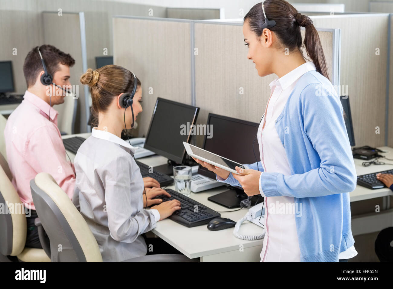Customer Service Executive Talking To Colleagues Working In Call Stock Photo