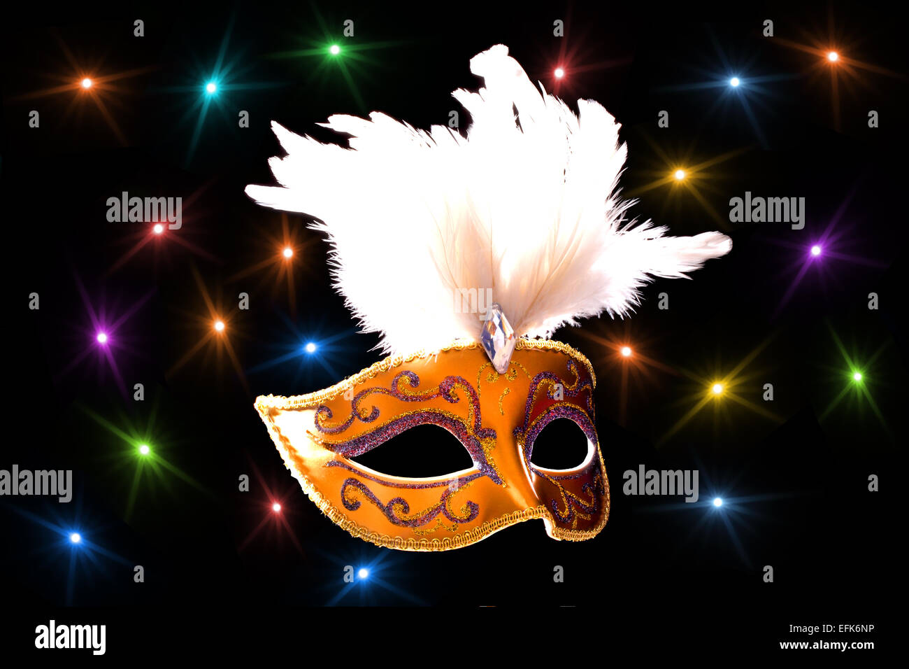 A Harlequin mask with colored lights in the background Stock Photo