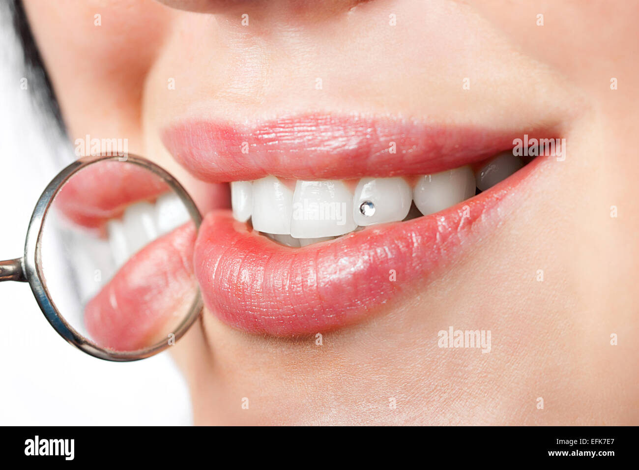 dental mouth mirror near healthy white woman teeth with precious stone on it Stock Photo