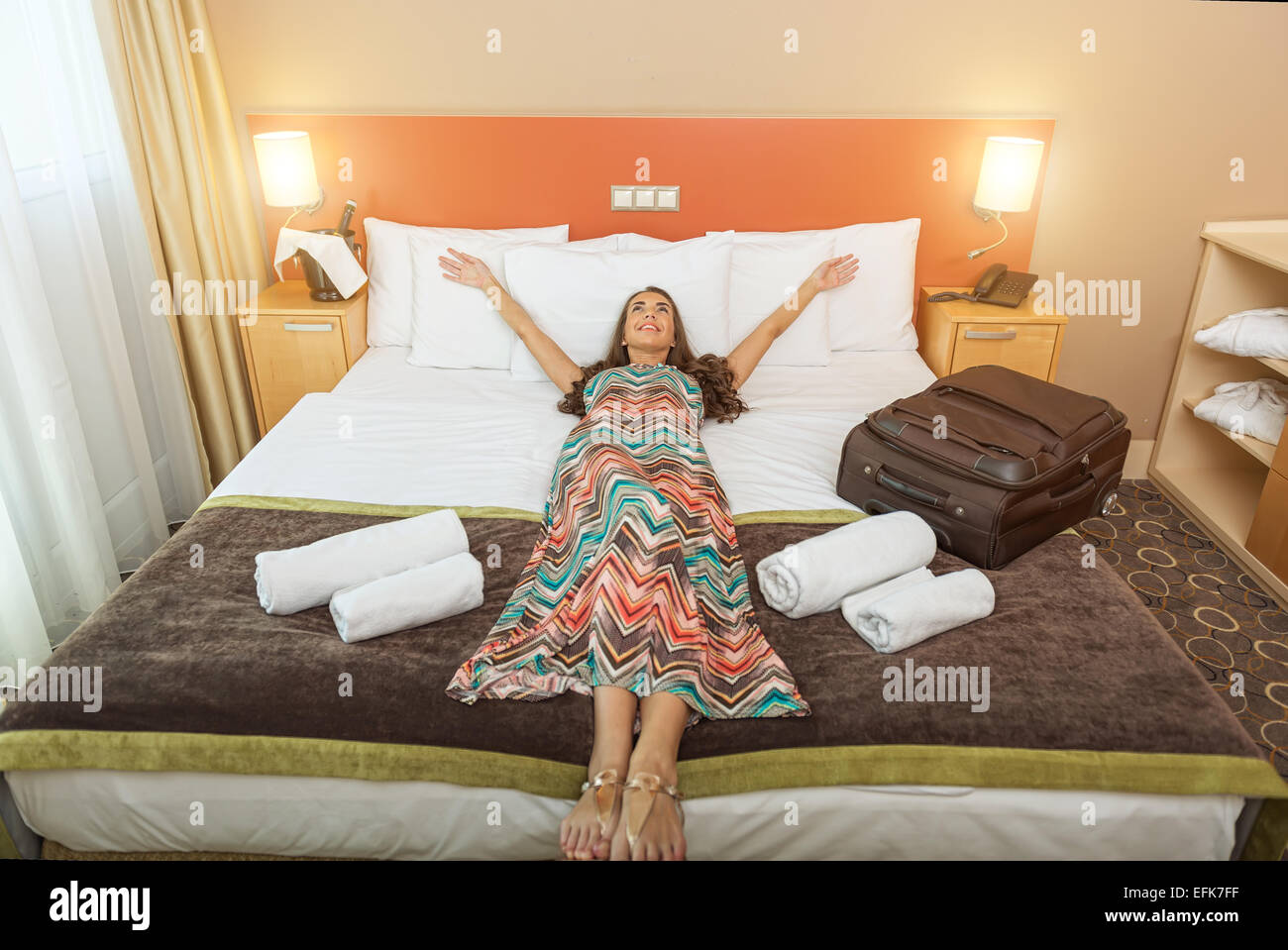 Young woman lying in the bed of a hotel room Stock Photo