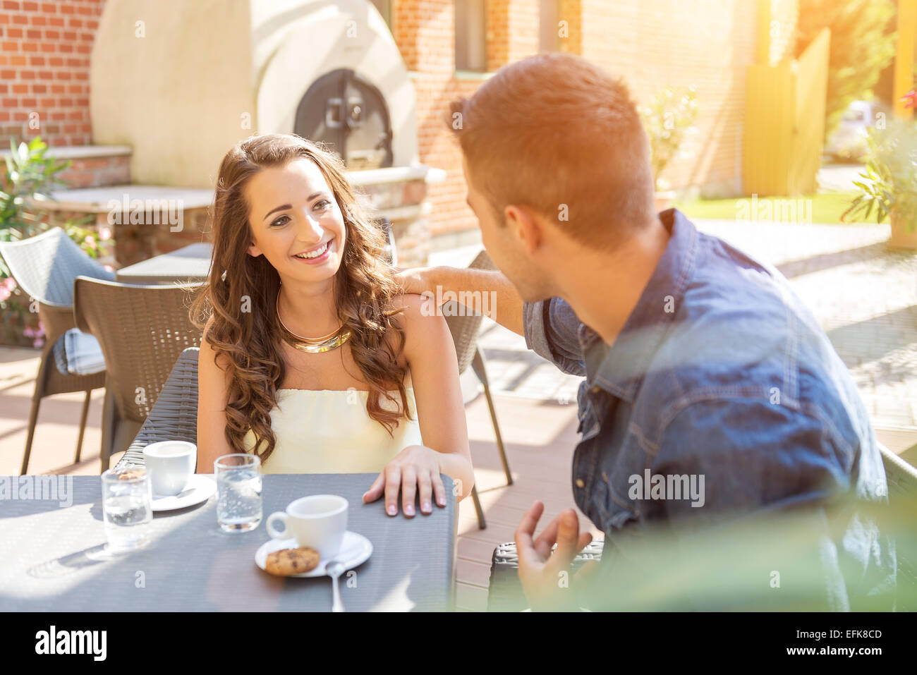 Young couple talking on the terrace of the restaurant, while eating Stock Photo