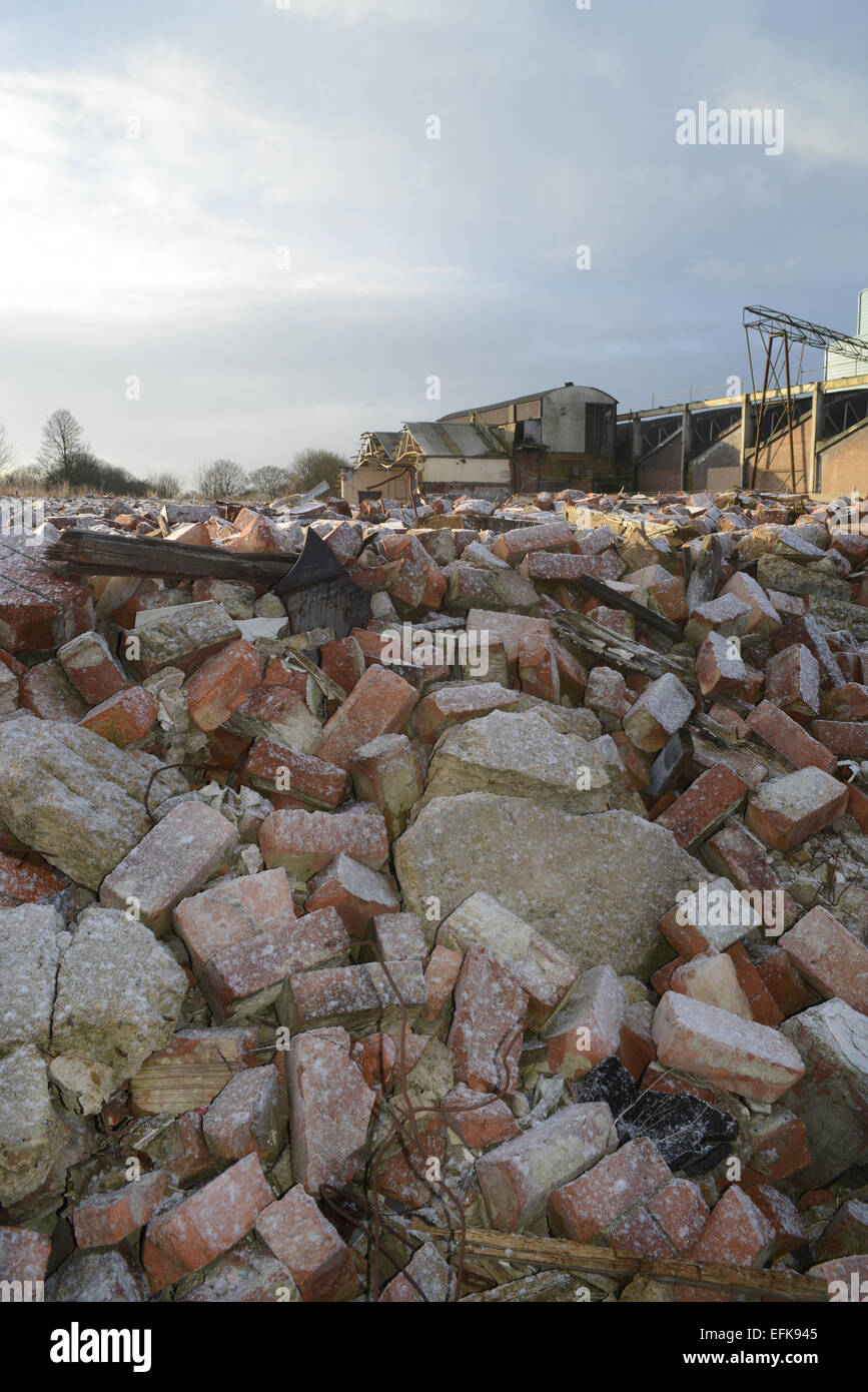 piles of rubble on derelict land and factory building covered by winter snow near selby yorkshire united kingdom Stock Photo