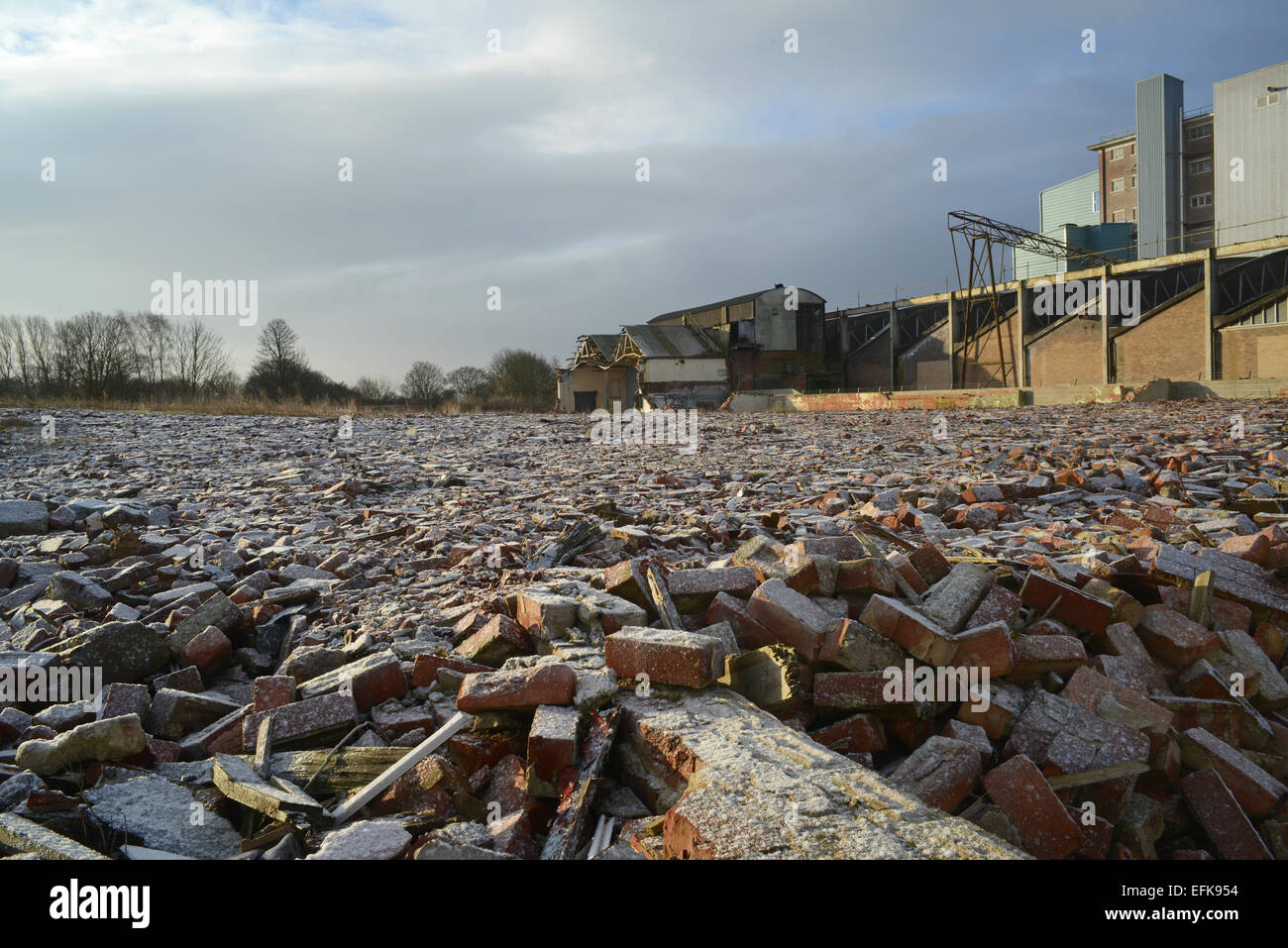 piles of rubble on derelict land and factory building covered by winter