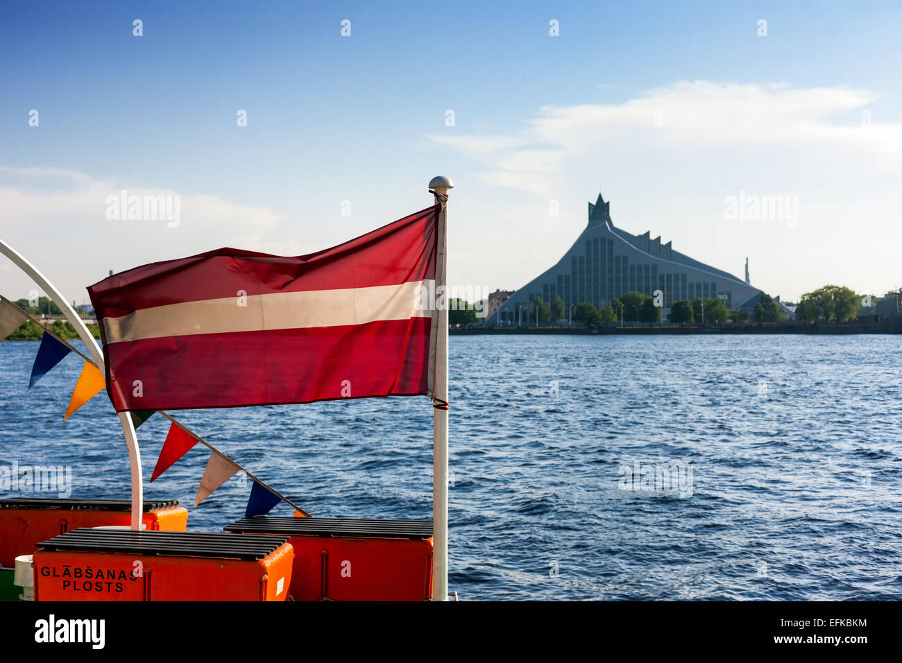 The national flag of Latvia on the ship on the background of the National Library in Riga Stock Photo