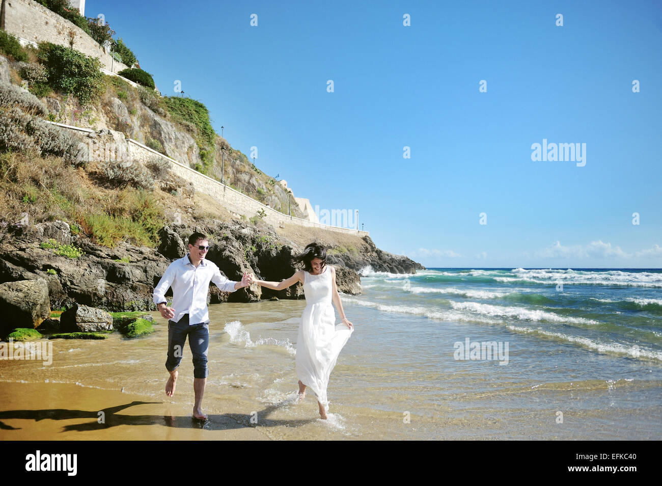 happy couple holding hands running on the beach near sea in wedding day ...