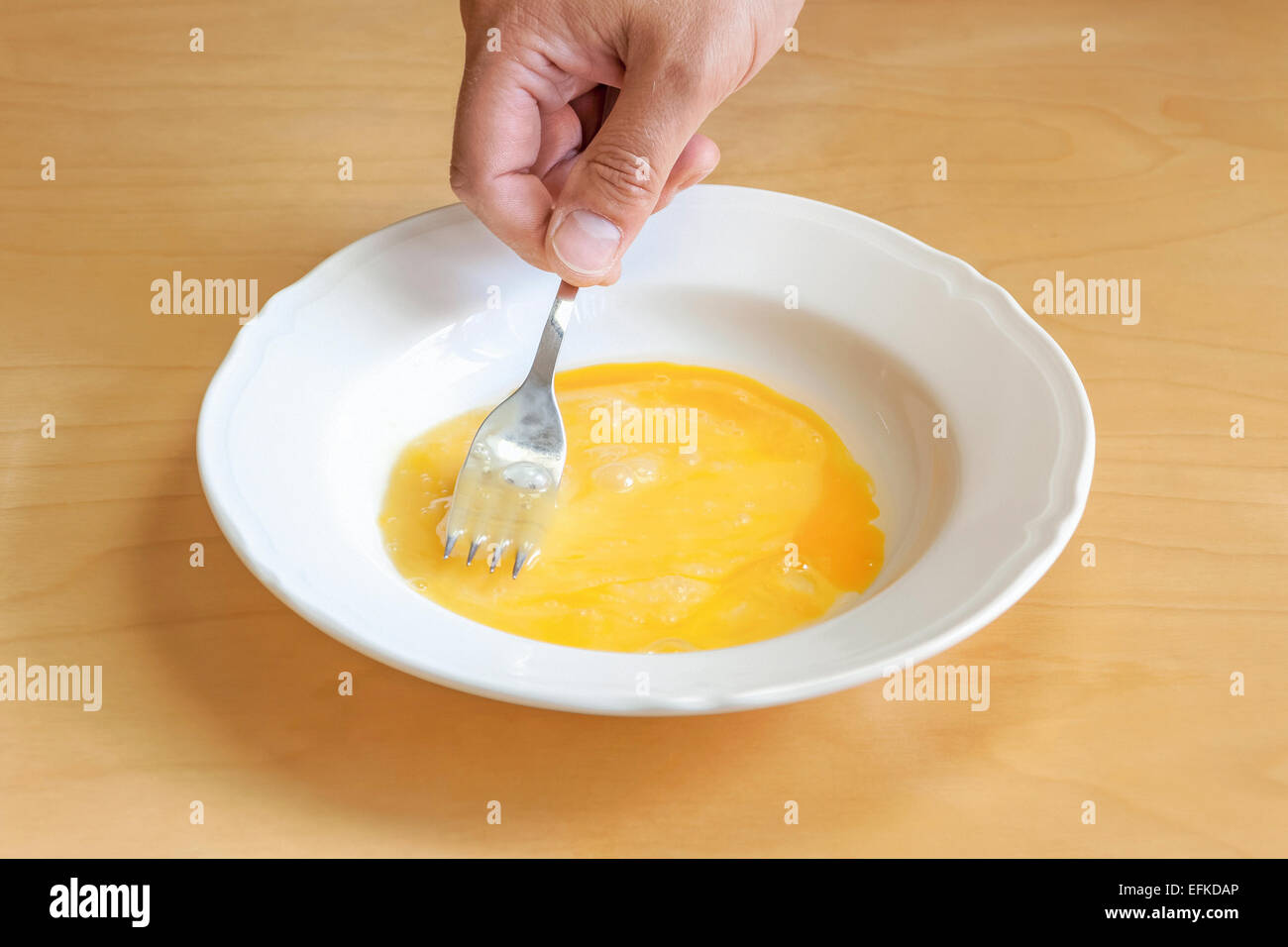 Preparing pork schnitzel whisking eggs in a bowl or plate Stock Photo