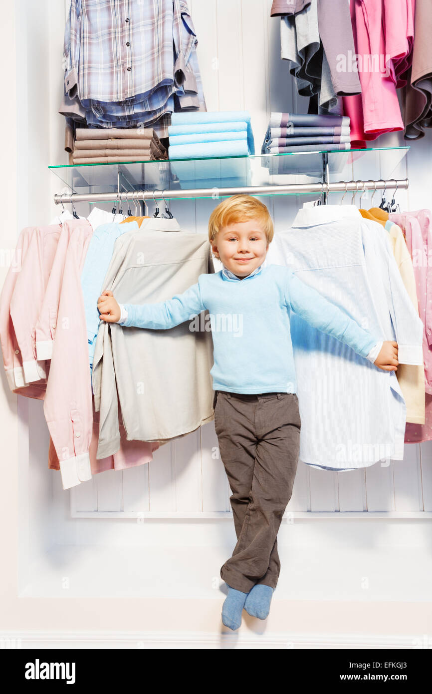 Boy standing among clothes on hangers and shelf Stock Photo - Alamy
