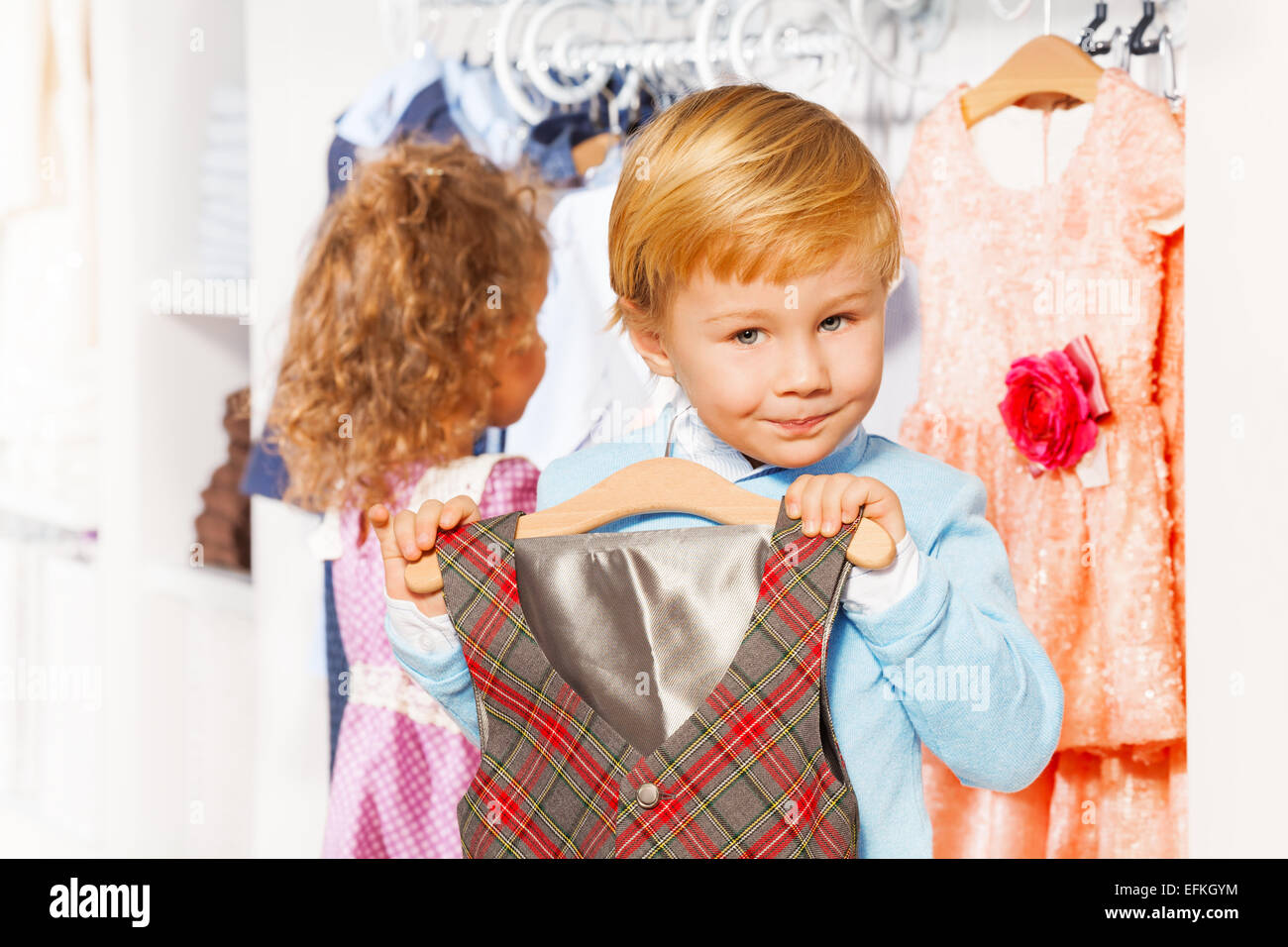 Boy with hanger and vest, girl choosing clothes Stock Photo