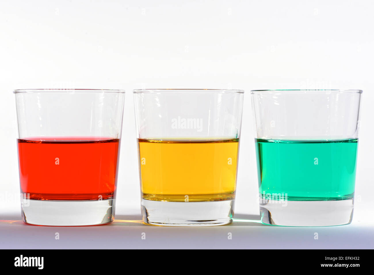 Three tumblers containing colored liquid - red, yellow / amber and green Stock Photo