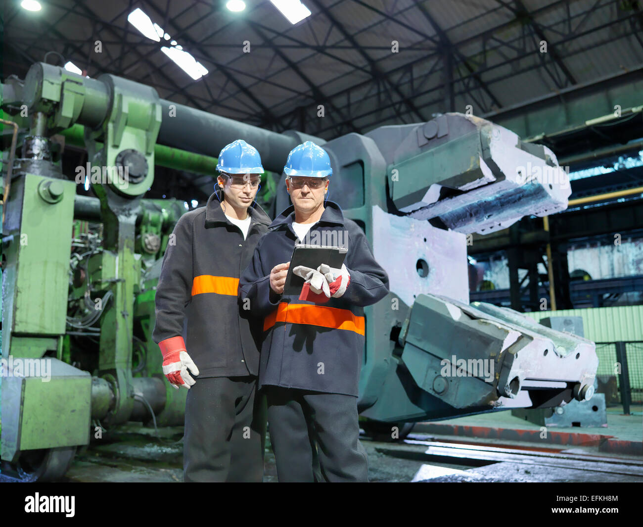 Steelworkers with digital tablet in front of forge in steelworks Stock Photo