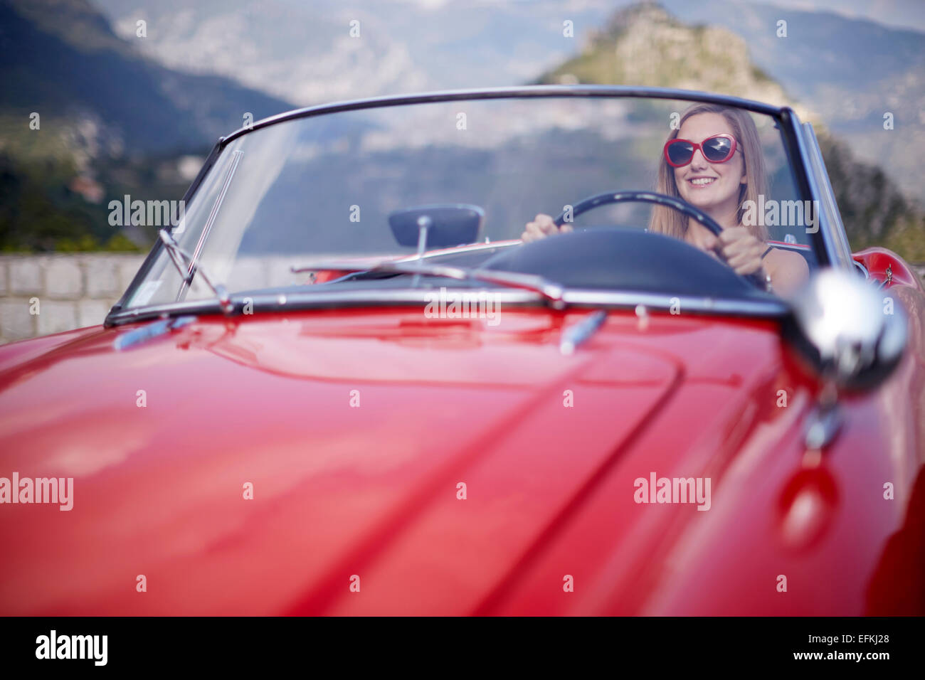 Young woman driving a vintage classic sports car in the South of France