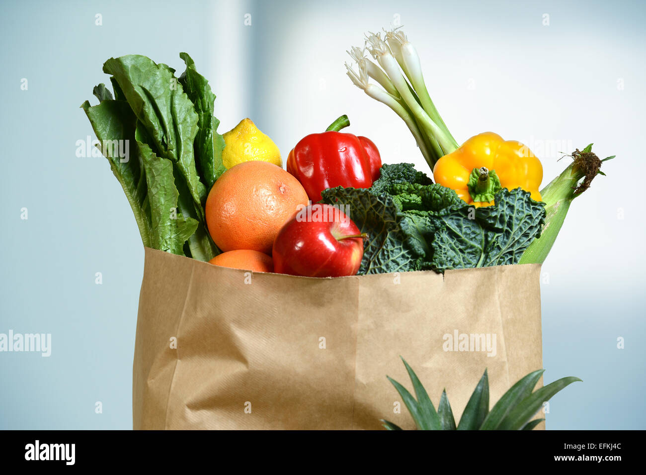Assortment of fresh produce in grocery paper bag by window Stock Photo