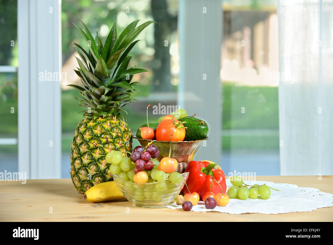 Various fruits and vegetables on table near window Stock Photo