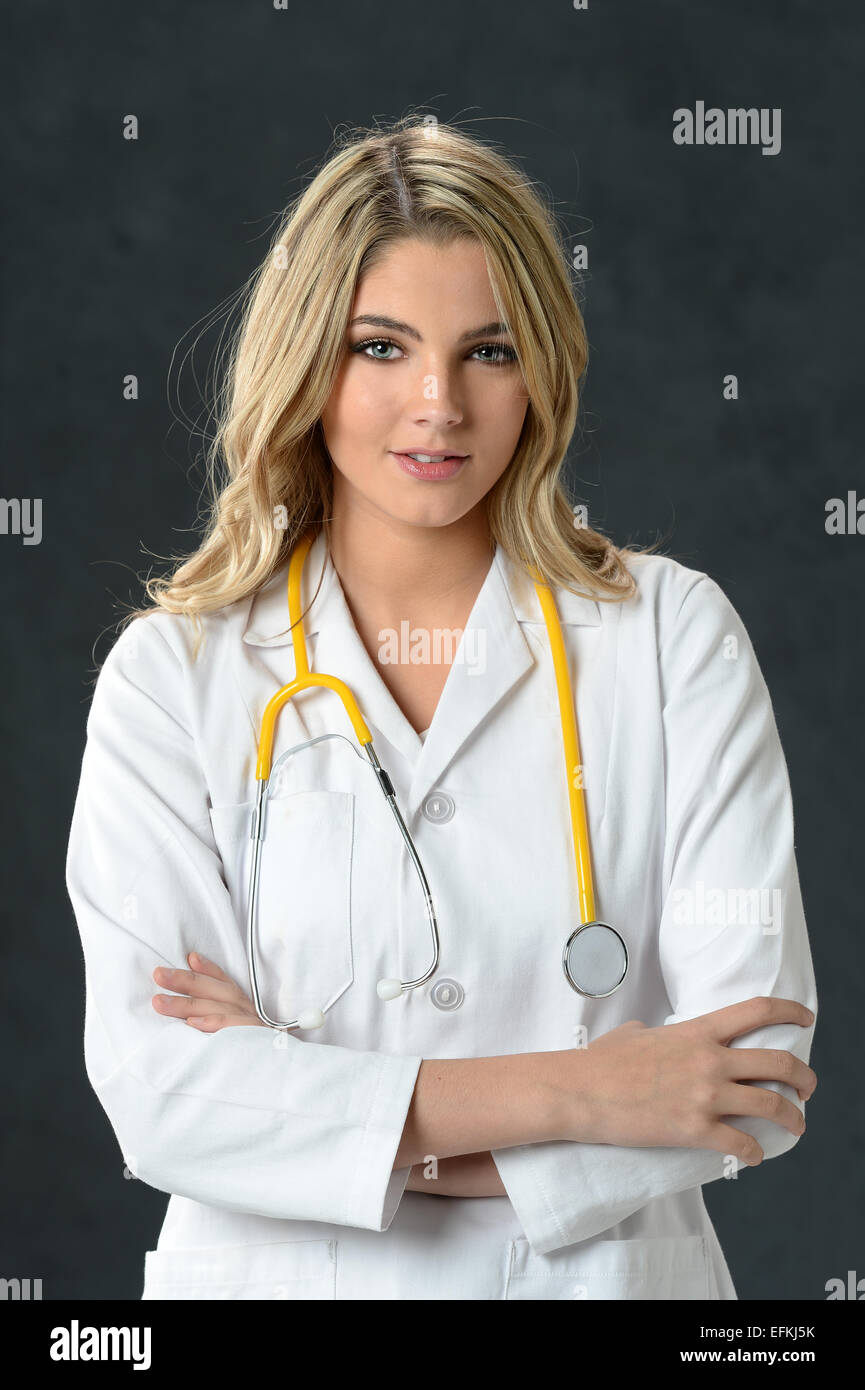 Young nurse or doctor smiling with arms crossed over dark background Stock Photo