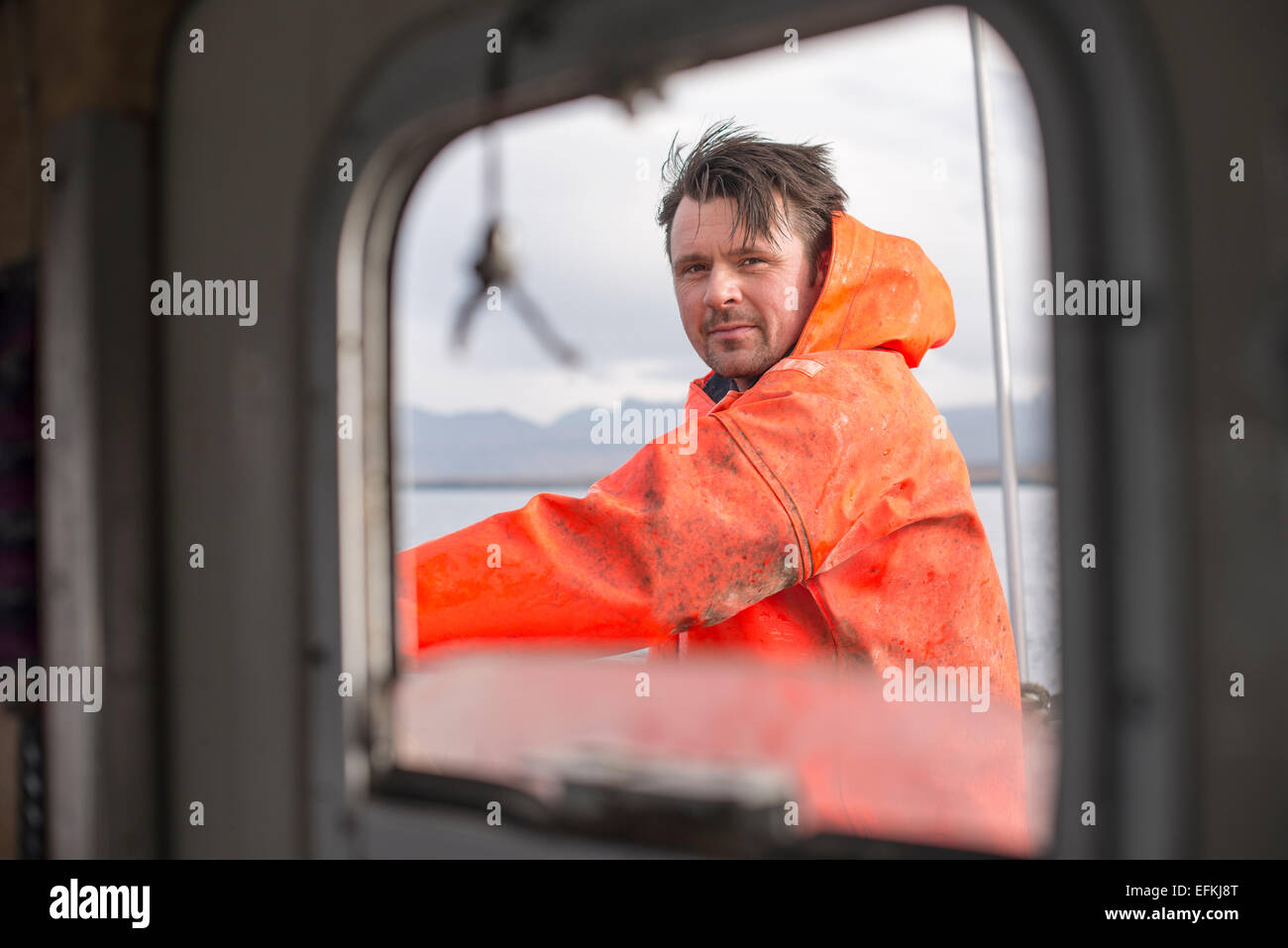 Fisherman seen through fishing boat window Stock Photo