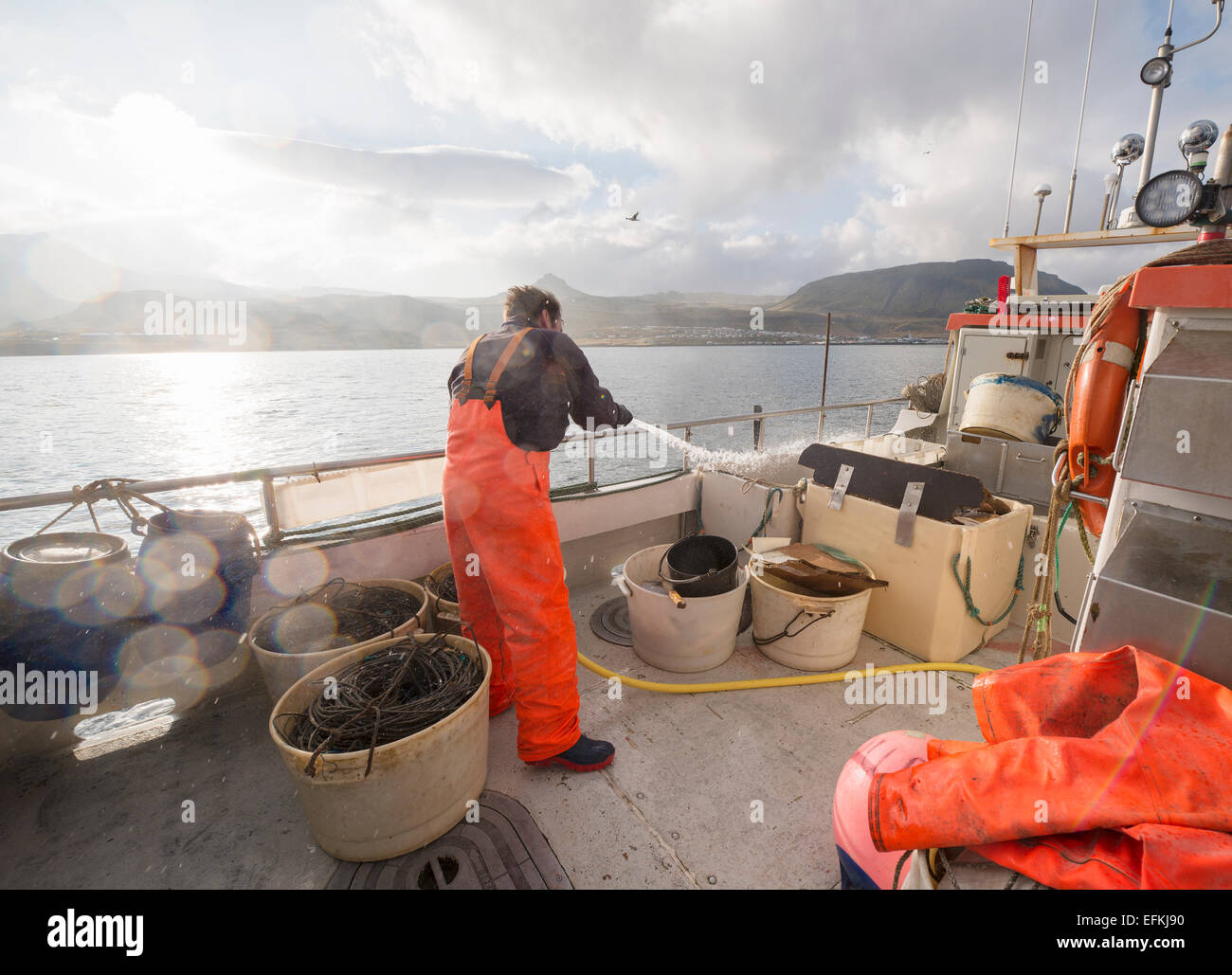 Fisherman hosing down fishing boat Stock Photo