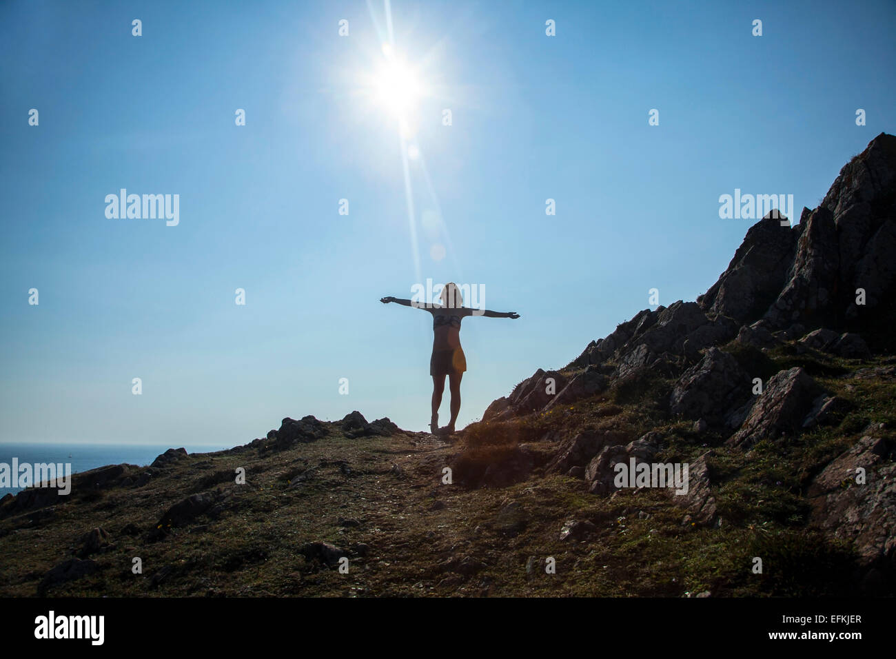 Mid adult woman standing on cliff edge, arms outstretched Stock Photo ...