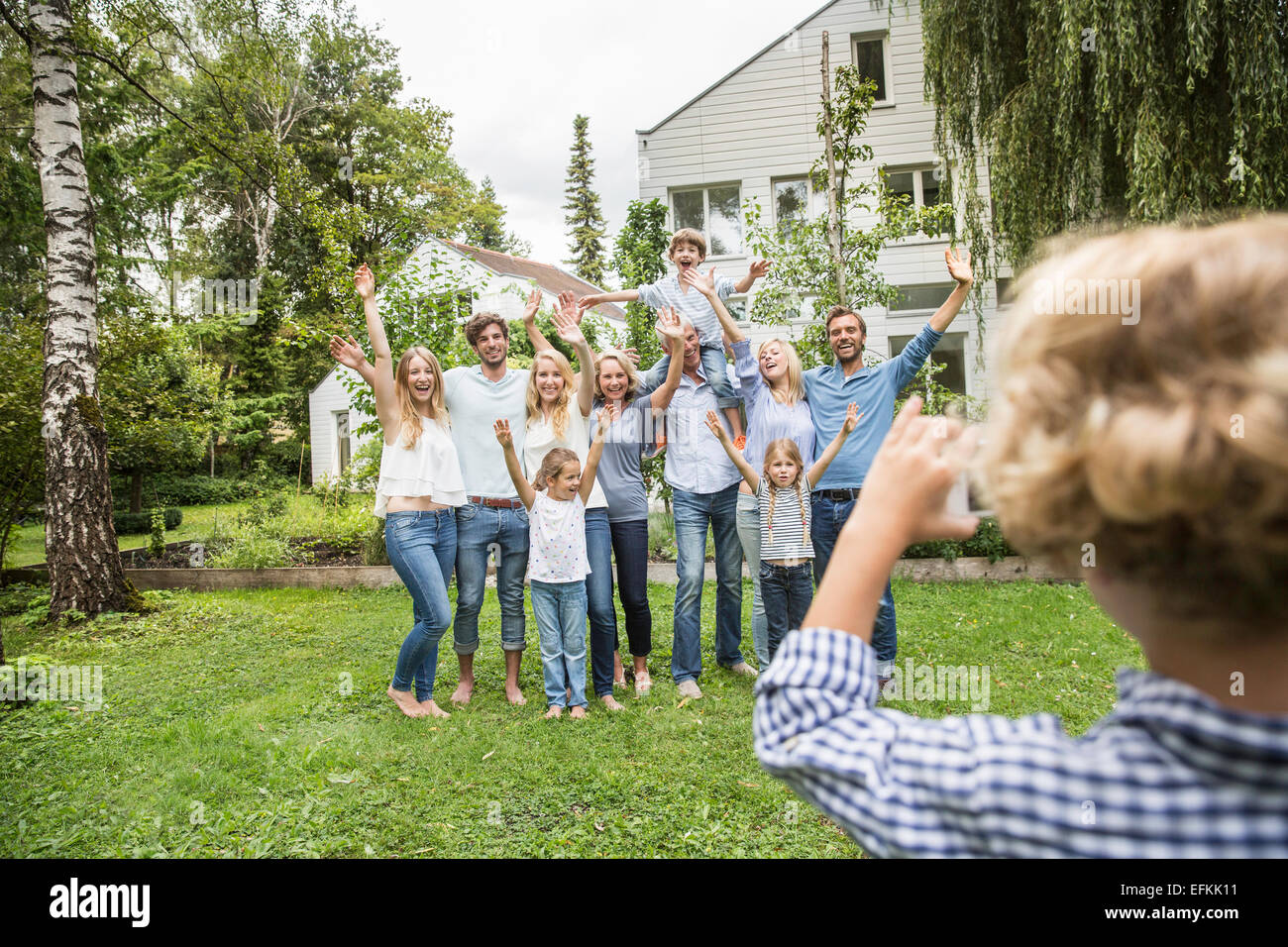 Boy taking photo of three generational family in garden Stock Photo