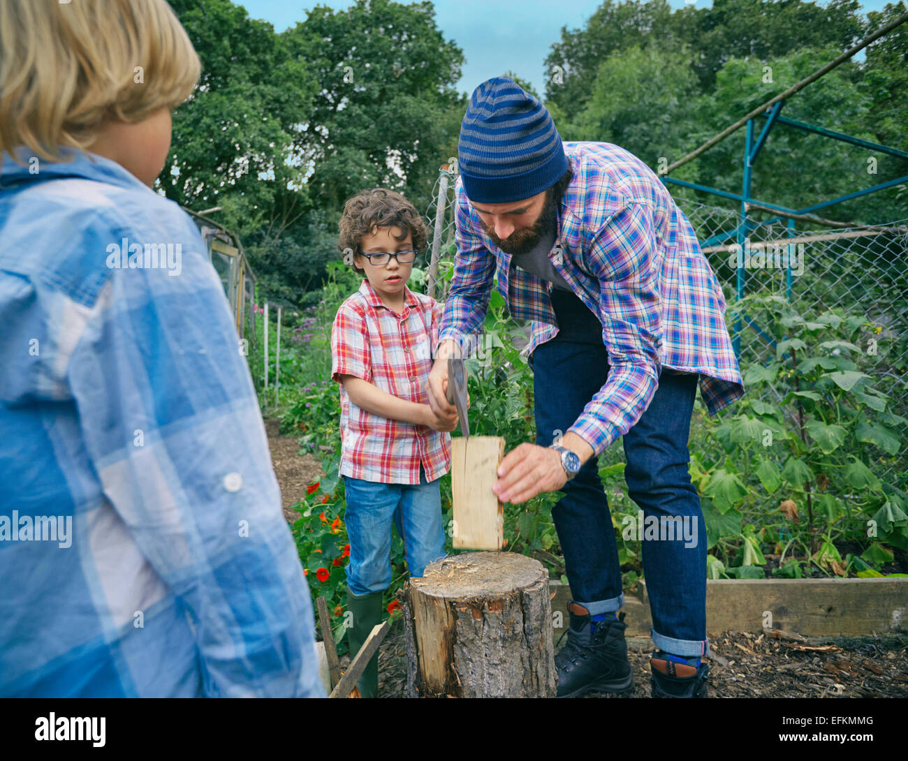 Father explaining how to chop logs to sons Stock Photo