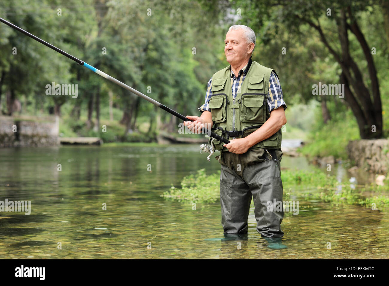 Cheerful mature fisherman fishing in a river outdoors Stock Photo