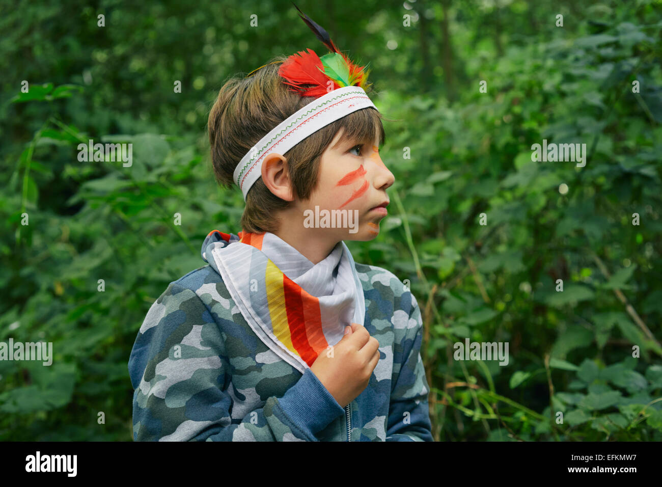 Boy dressed up in face paint and playing in forest Stock Photo