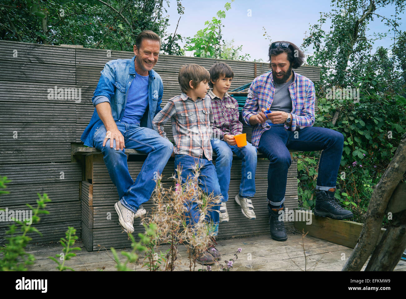 Male friends and sons taking a break on allotment Stock Photo