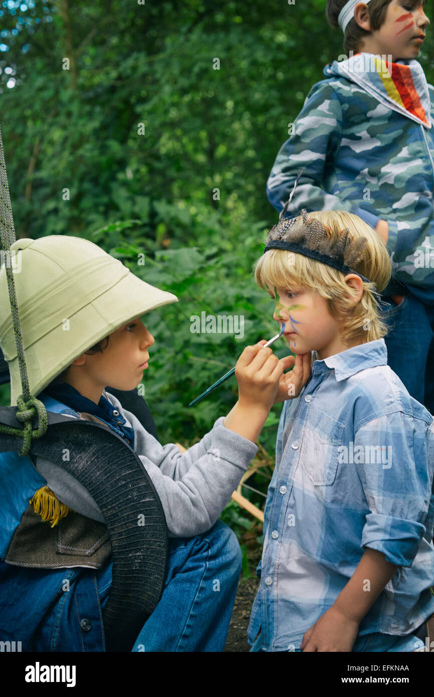 Three boys playing dress up in forest with face paint Stock Photo