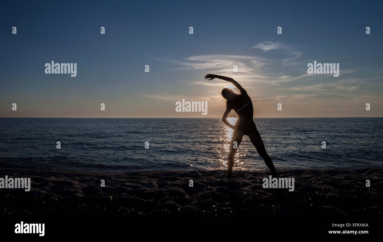 Young woman practicing yoga at sunset, Oristano, Sardinia, Italy Stock Photo