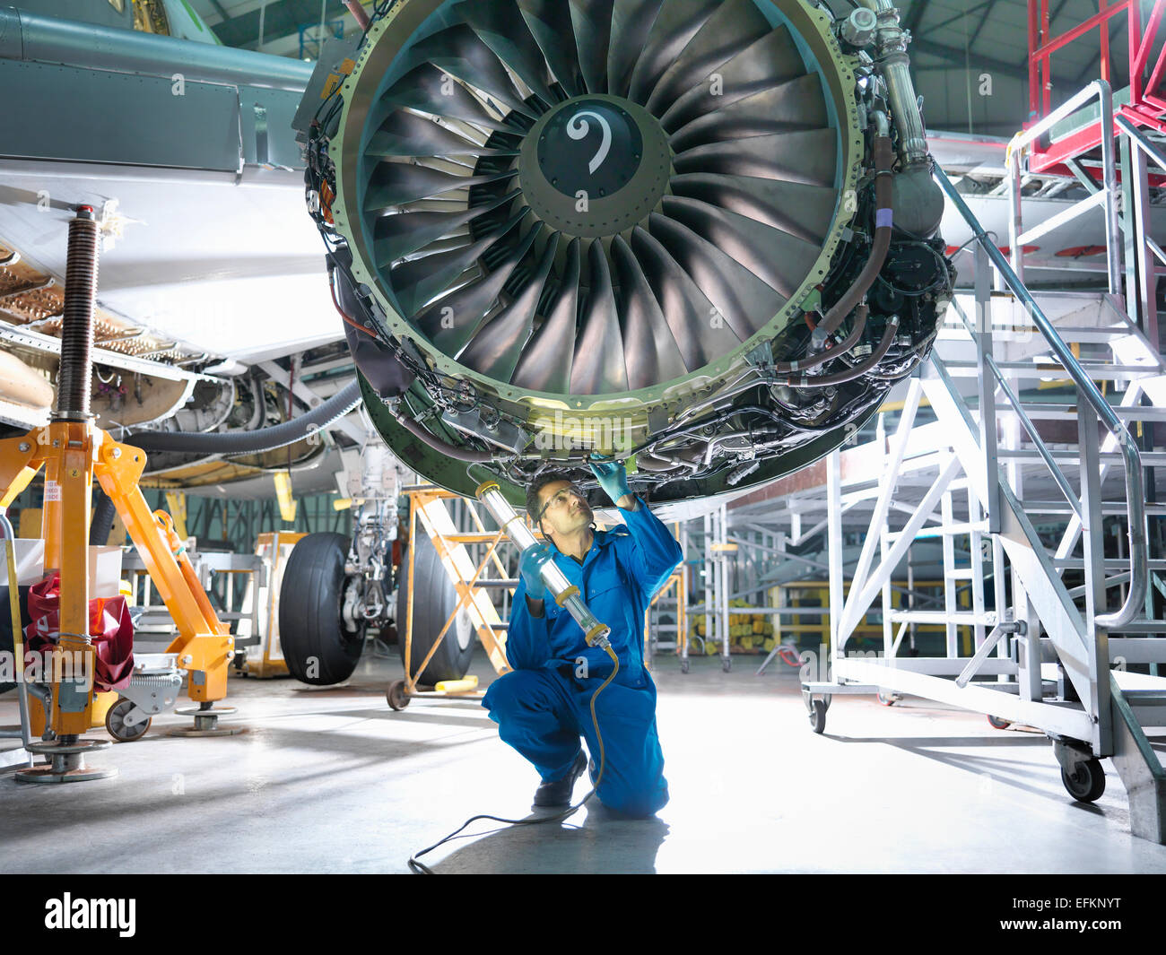 Engineer inspecting jet engine in aircraft maintenance factory Stock Photo