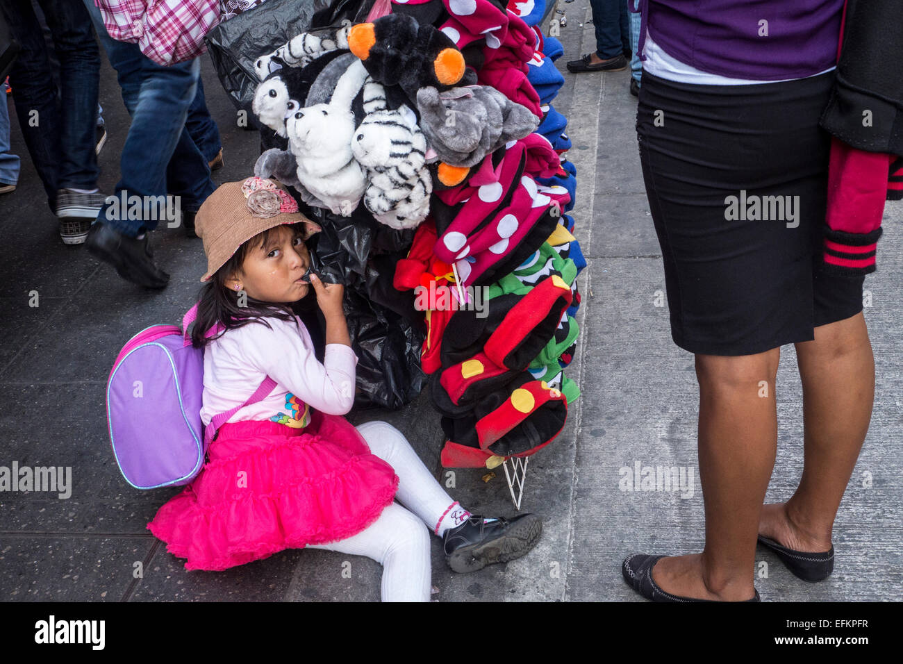 Girl sits beside soft toys in the centre of Guatemala City Stock Photo