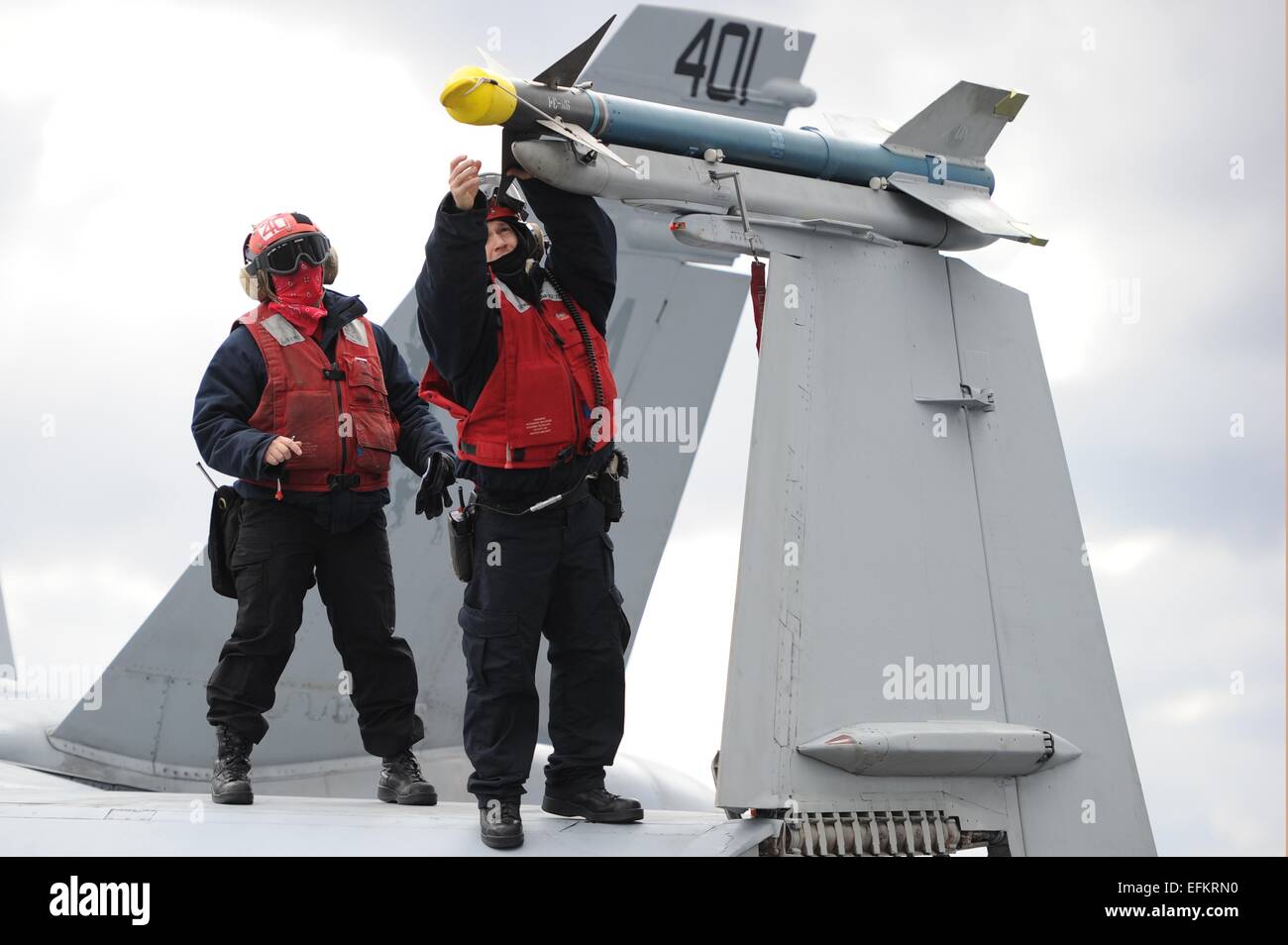 US Navy Ordananceman verify serial numbers on a Sidewinder practice missile while standing on an FA-18C Hornet aircraft aboard the aircraft carrier USS George H.W. Bush during training operations February 3, 2015 in the Atlantic Ocean. Stock Photo