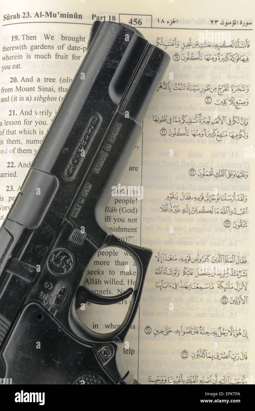 Handgun sits on top of an open Qu'ran - signifying radicalism and extremism of Muslims carrying out terrorist atrocities in the name of Allah Stock Photo