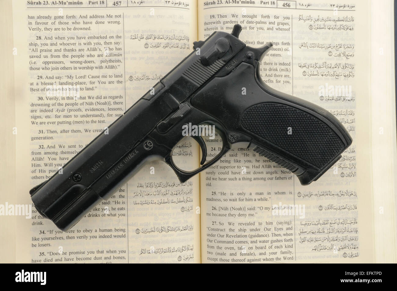 Handgun sits on top of an open Qu'ran - signifying radicalism and extremism of Muslims carrying out terrorist atrocities in the name of Allah (e.g. ISIS Daesh) Stock Photo
