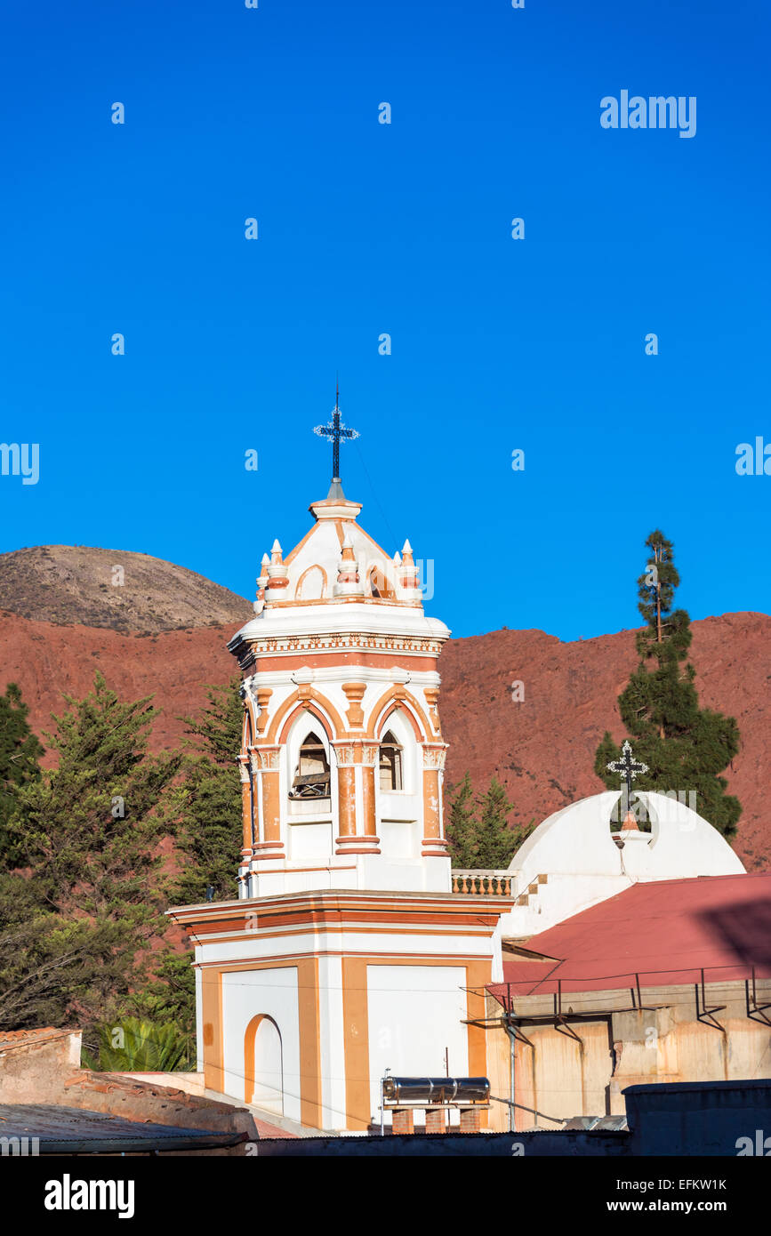 Spire of the cathedral in Tupiza, Bolivia with red hills in the background Stock Photo