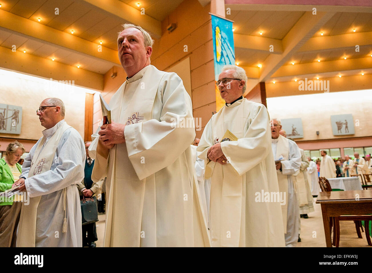 Priests wearing robes leave in line following mass. Stock Photo