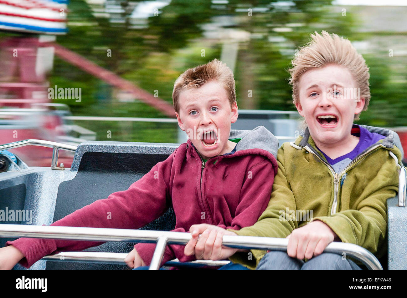 Two teenage boys (aged 14 and 13) scream with excitement while traveling at speed on a Cyclone fairground ride. Stock Photo