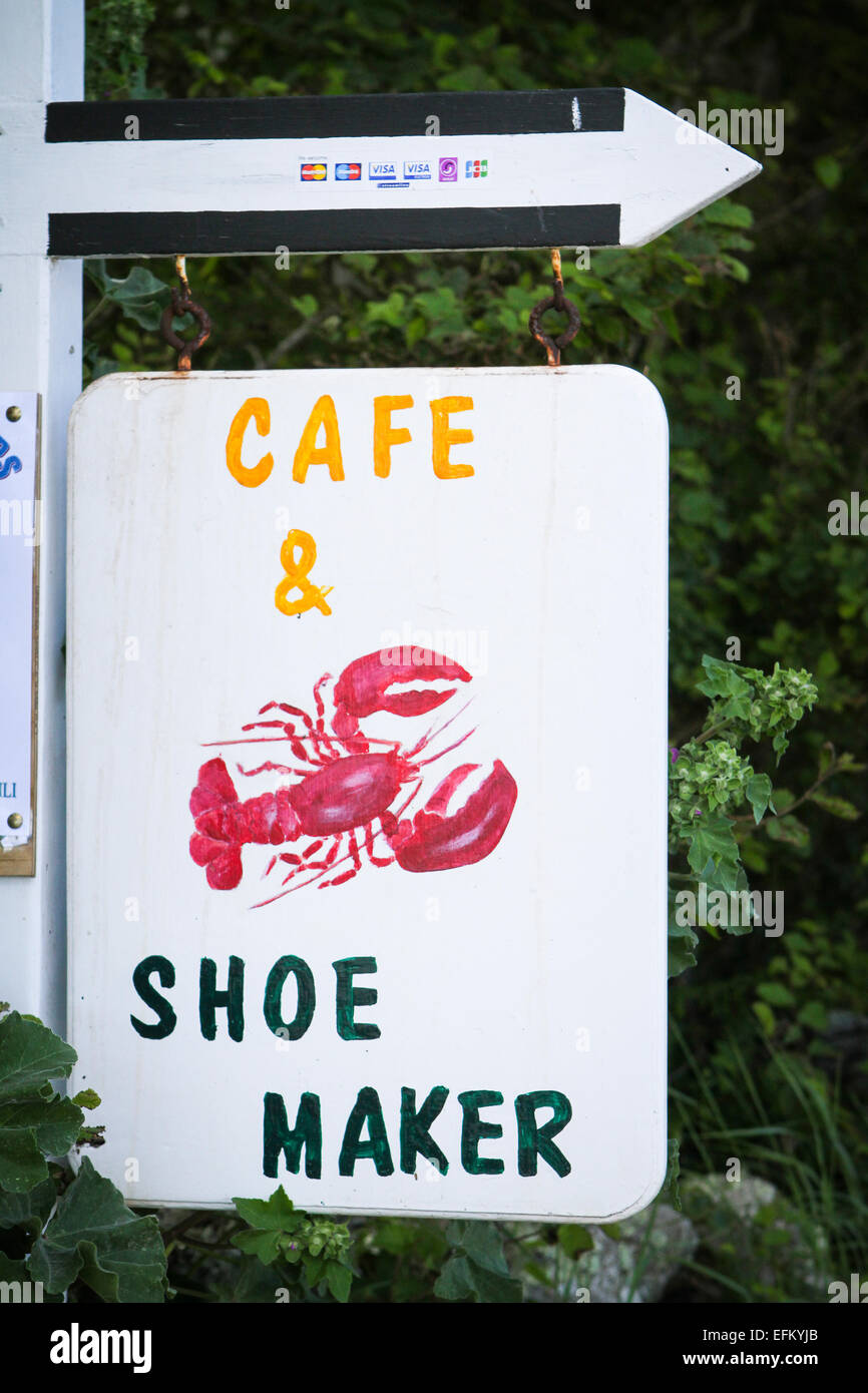 Handmade sign for cafe and shoe maker hanging from direction arrow, Isles of Scilly, Uk Stock Photo