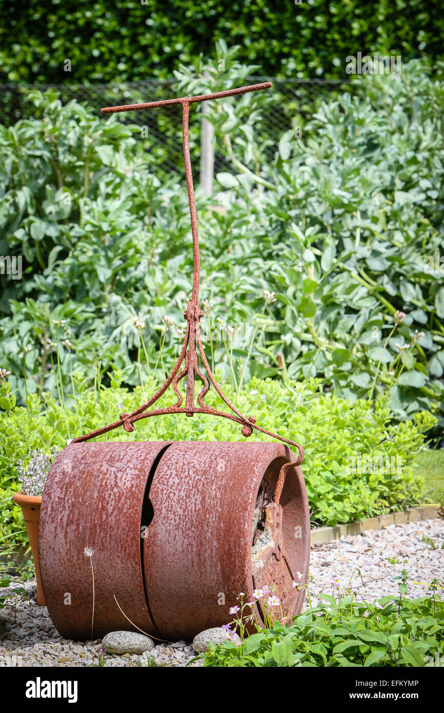 Rusting garden roller abandoned on garden path Stock Photo