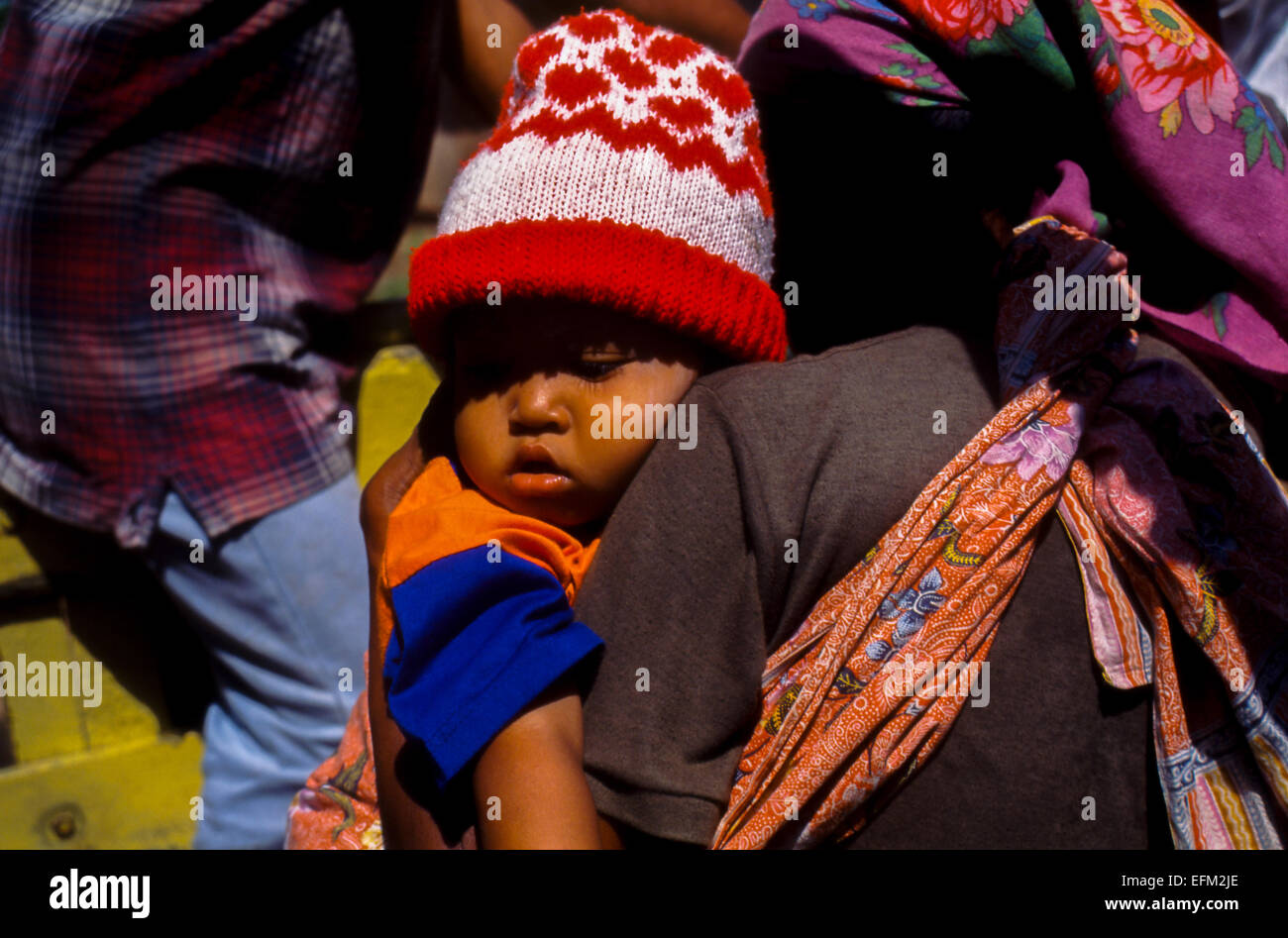 A baby sleeping on his mother's arm as they board a truck used as public transportation near Meru Betiri National Park, East Java, Indonesia. Stock Photo