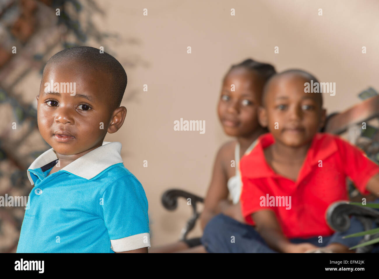 Little boy with his older brother and sister, who are twins, sitting behind him. Stock Photo