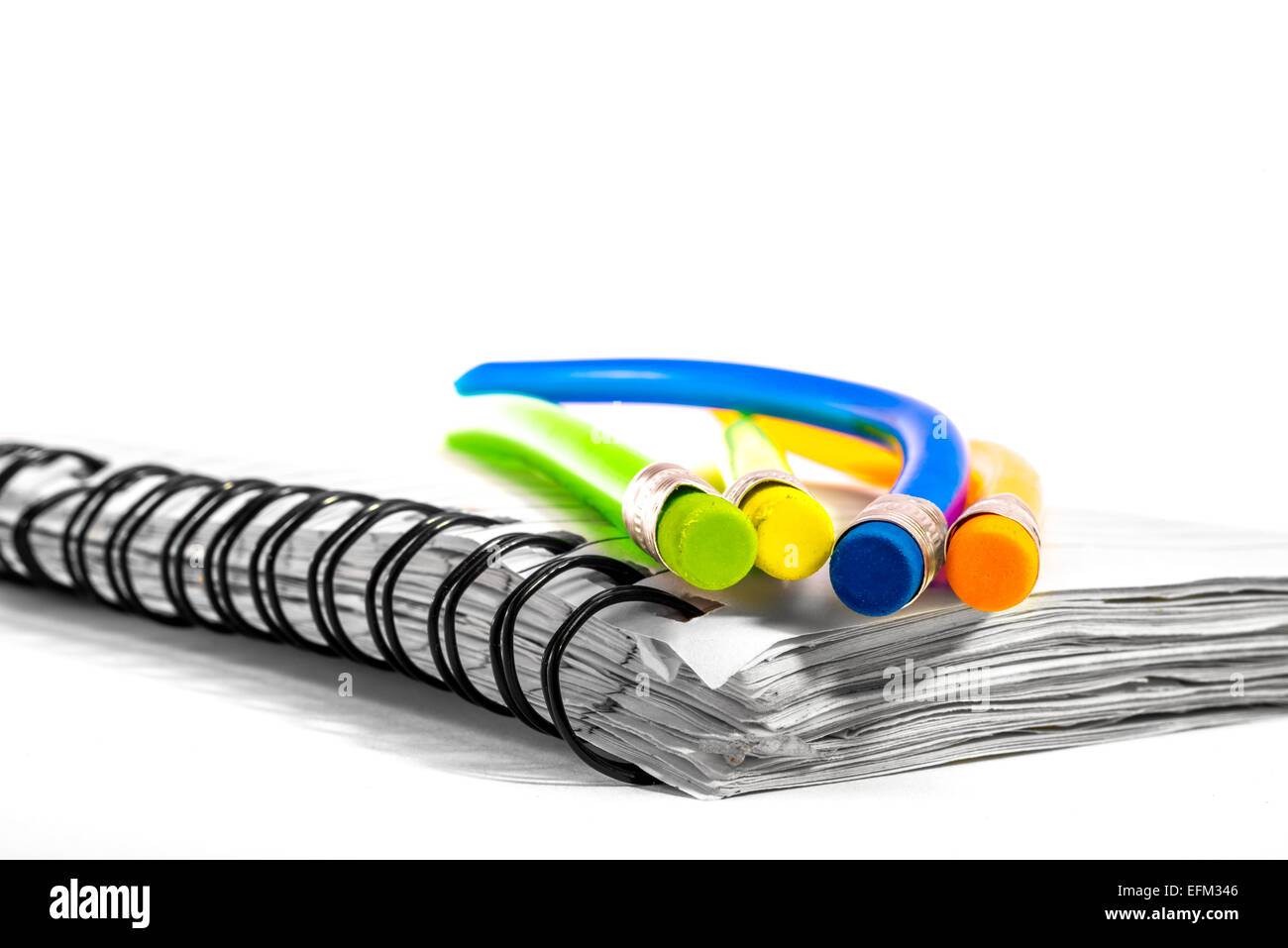 Colorful bend pencils together on a notebook. Stock Photo
