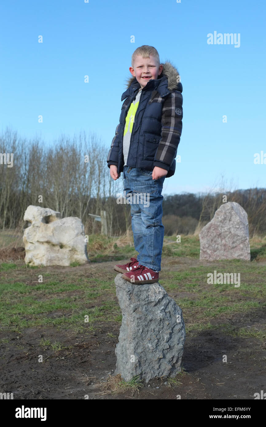 Boy aged six  standing on top of a rock at Brockholes Nature Reserve near Preston, Lancashire Stock Photo