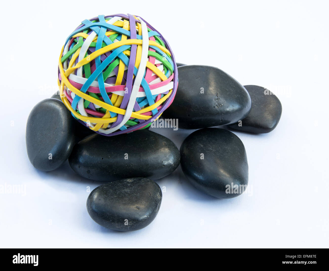 Ball of rubber bands on a pile of black stones Stock Photo - Alamy